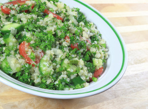 Quinoa Tabouleh salad in a bowl sitting on a wooden table.