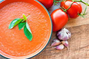A bowl of tomato soup gaspacho with basil, tomatoes and garlic
